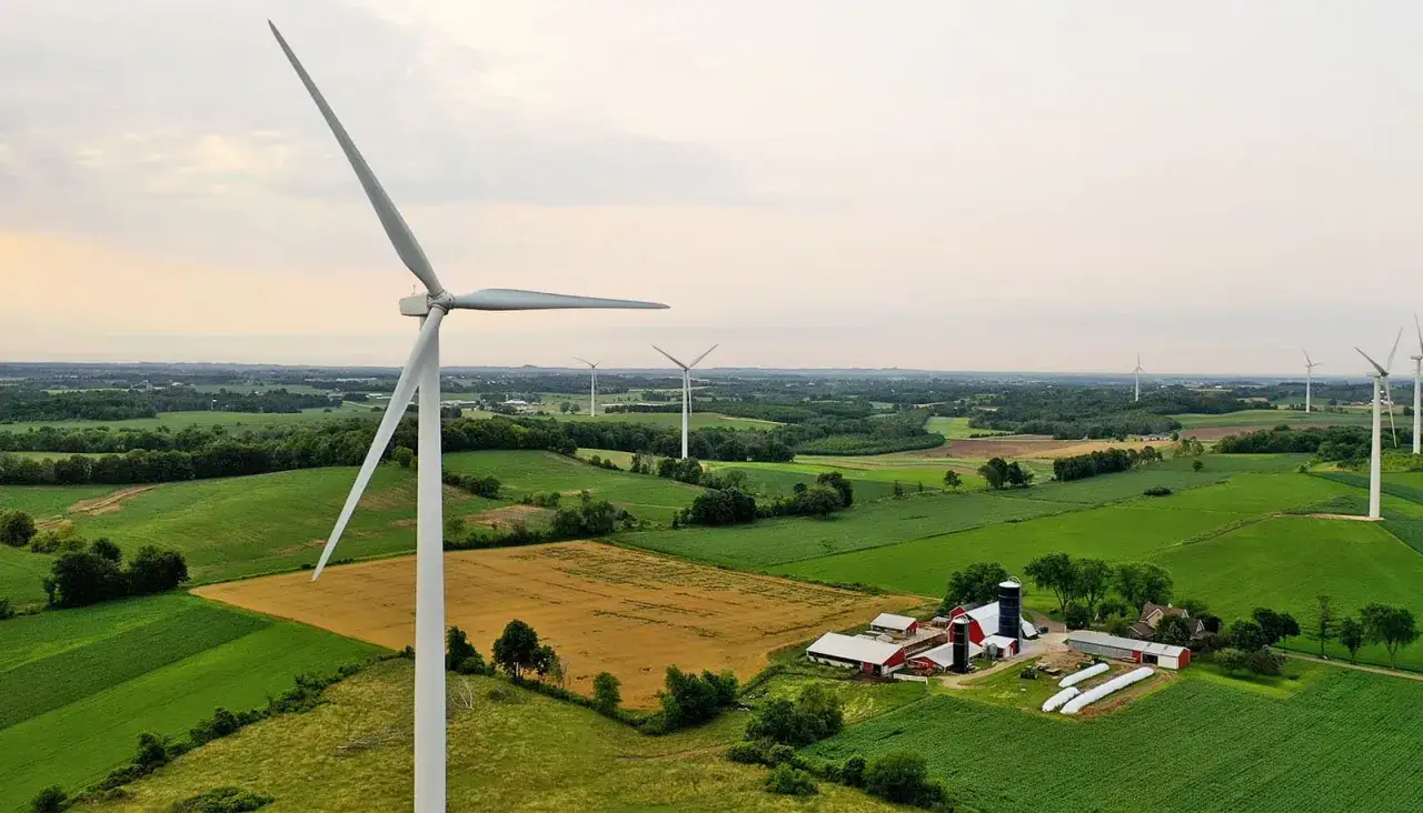 Krajobraz z farmą i wiatrakami. Czy wiatraki są szkodliwe? Tutaj pracują na rzecz czystej energii, nie szkodząc przyrodzie.