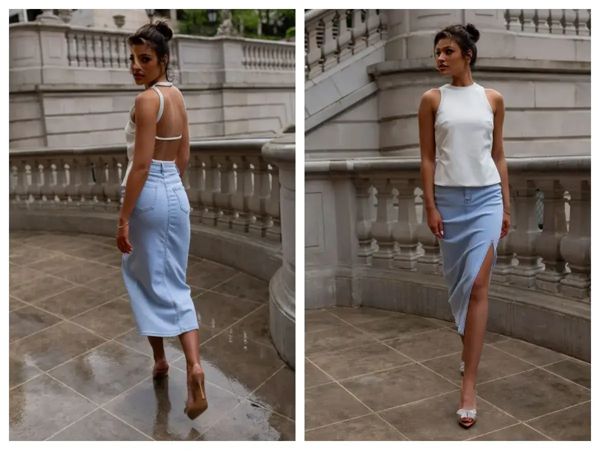 Elegancka spódnica jeansowa midi z rozcięciem, idealna do letnich stylizacji. Modelka prezentuje ją z białym topem na tle kamiennych schodów.