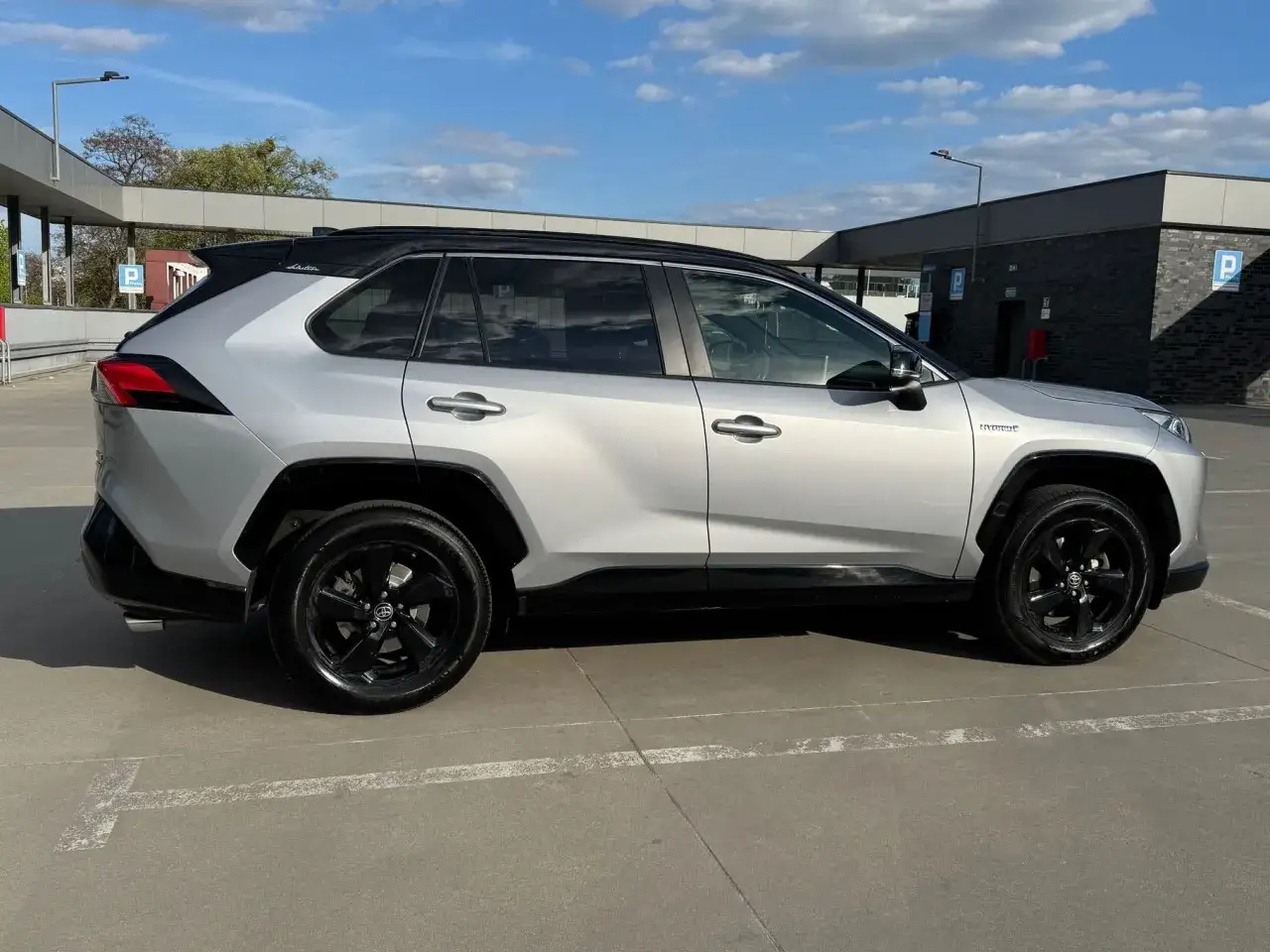 Srebrna Toyota RAV4 Hybrid z czarnym dachem i felgami, gotowa do cesji leasingu.