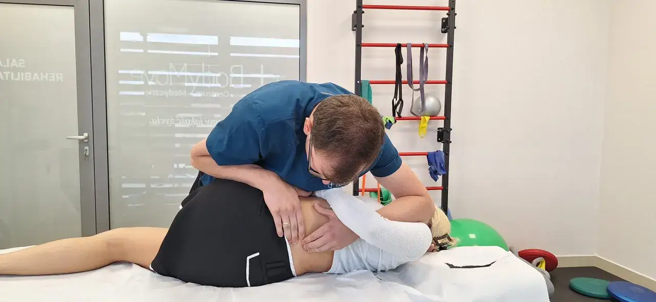 Fizjoterapeuta wykonuje terapię manualną u pacjentki z bólem kręgosłupa.
