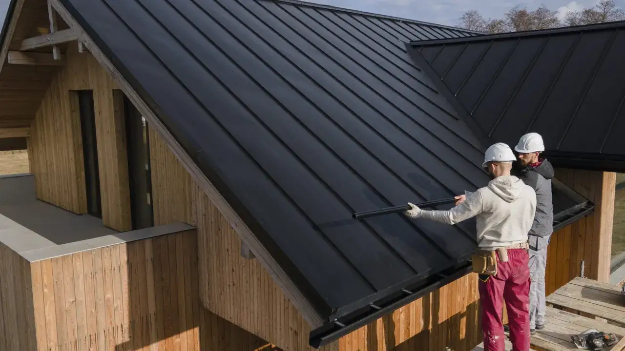 Dwóch budowlańców w kaskach montuje czarny dach. Zastanawiasz się, ile waży dachówka?