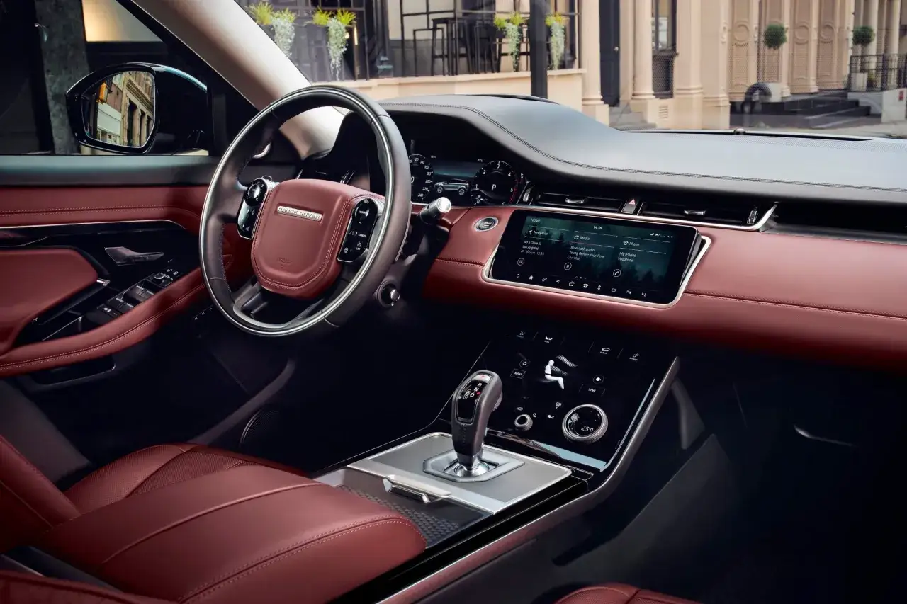Wnętrze Land Rover Evoque z czerwoną sk&oacute;rzaną tapicerką, nowoczesnym panelem sterowania i ekranem dotykowym.