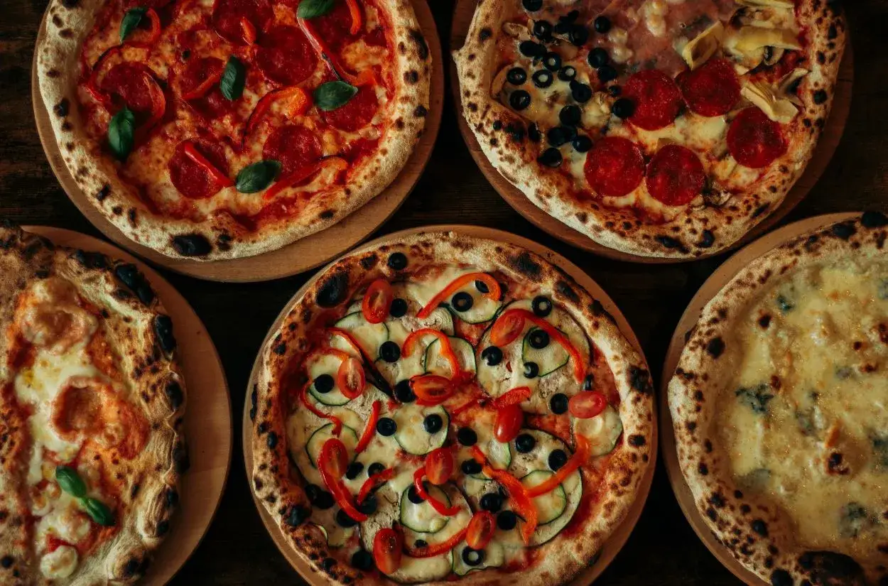 Pięć apetycznych pizz, w tym jedna z salami i bazylią, przypominająca o tym, gdzie powstała pizza.