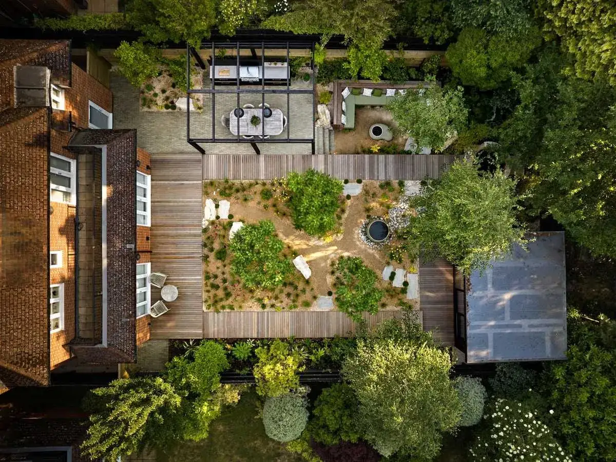 Nowoczesny ogr&oacute;d z tarasem, pergolą, miejscem do siedzenia i grillem.