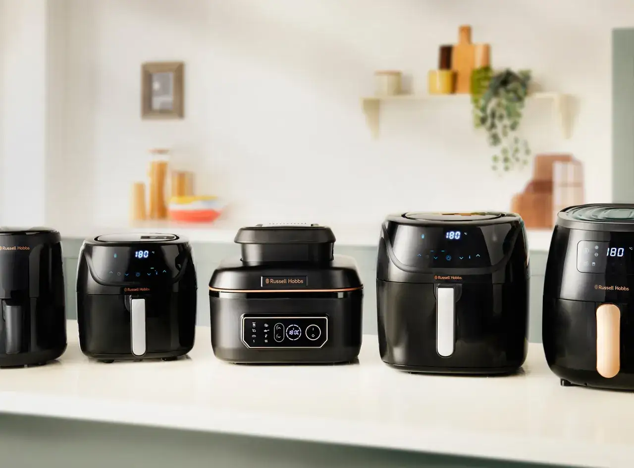 Pięć czarnych frytkownic beztłuszczowych Russell Hobbs ustawionych w rzędzie. Idealne do rankingu airfryer.