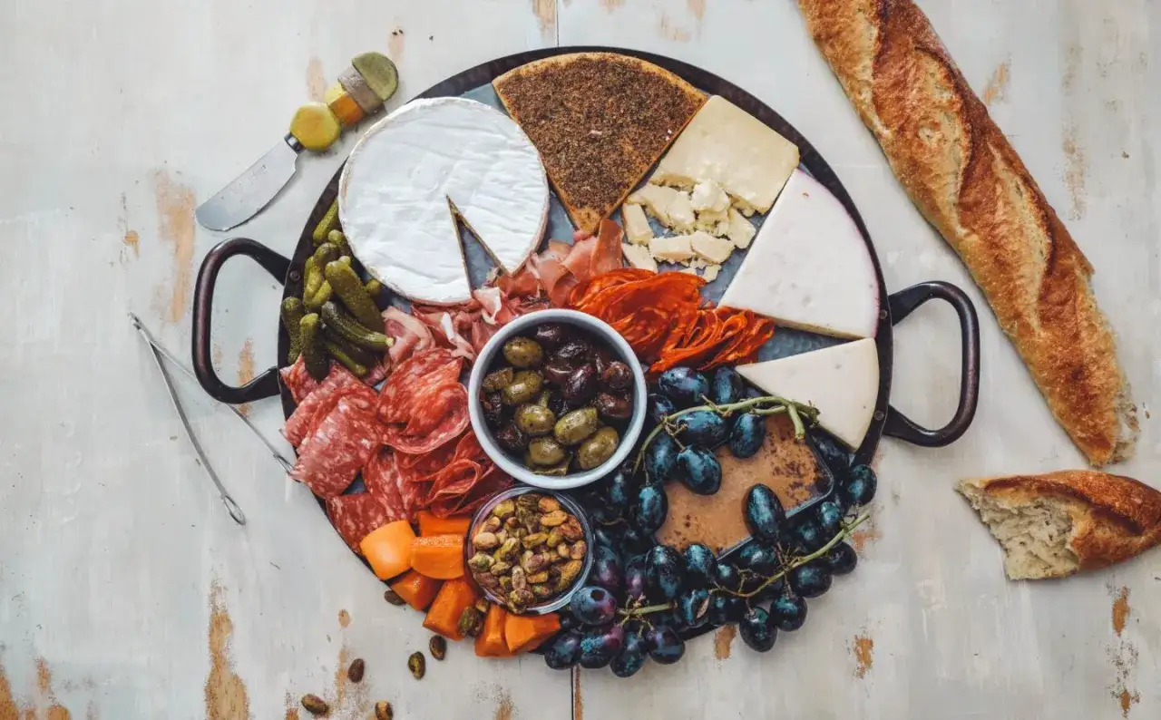 Deska serów i wędlin, oliwki, winogrona, krakersy i bagietka – idealne menu, co warto zjeść w Paryżu.