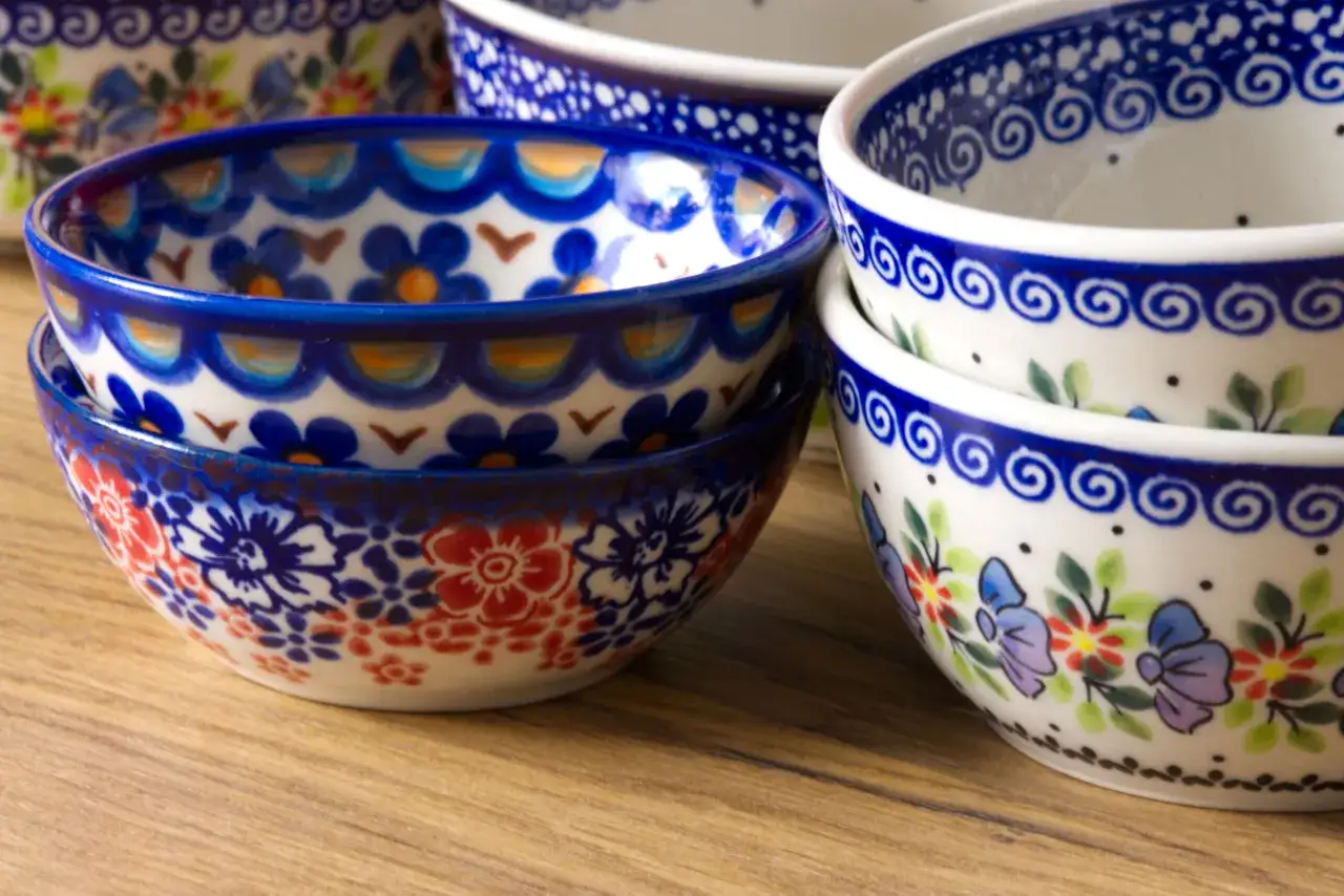 Stos ceramicznych naczyń, pięknie zdobionych tradycyjną polską ceramiką.