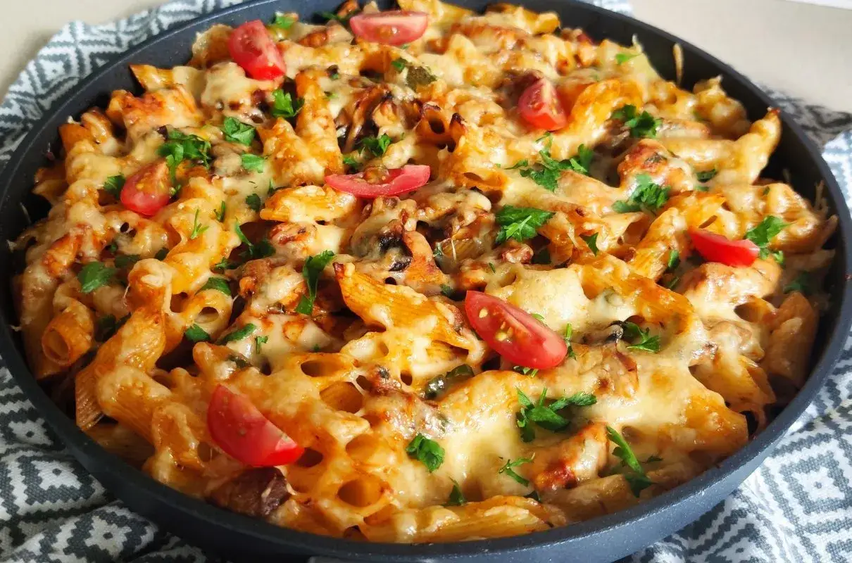 Penne zapiekane z kurczakiem, pieczarkami i pomidorkami, posypane serem i natką pietruszki. Idealne co z pieczarkami na obiad!