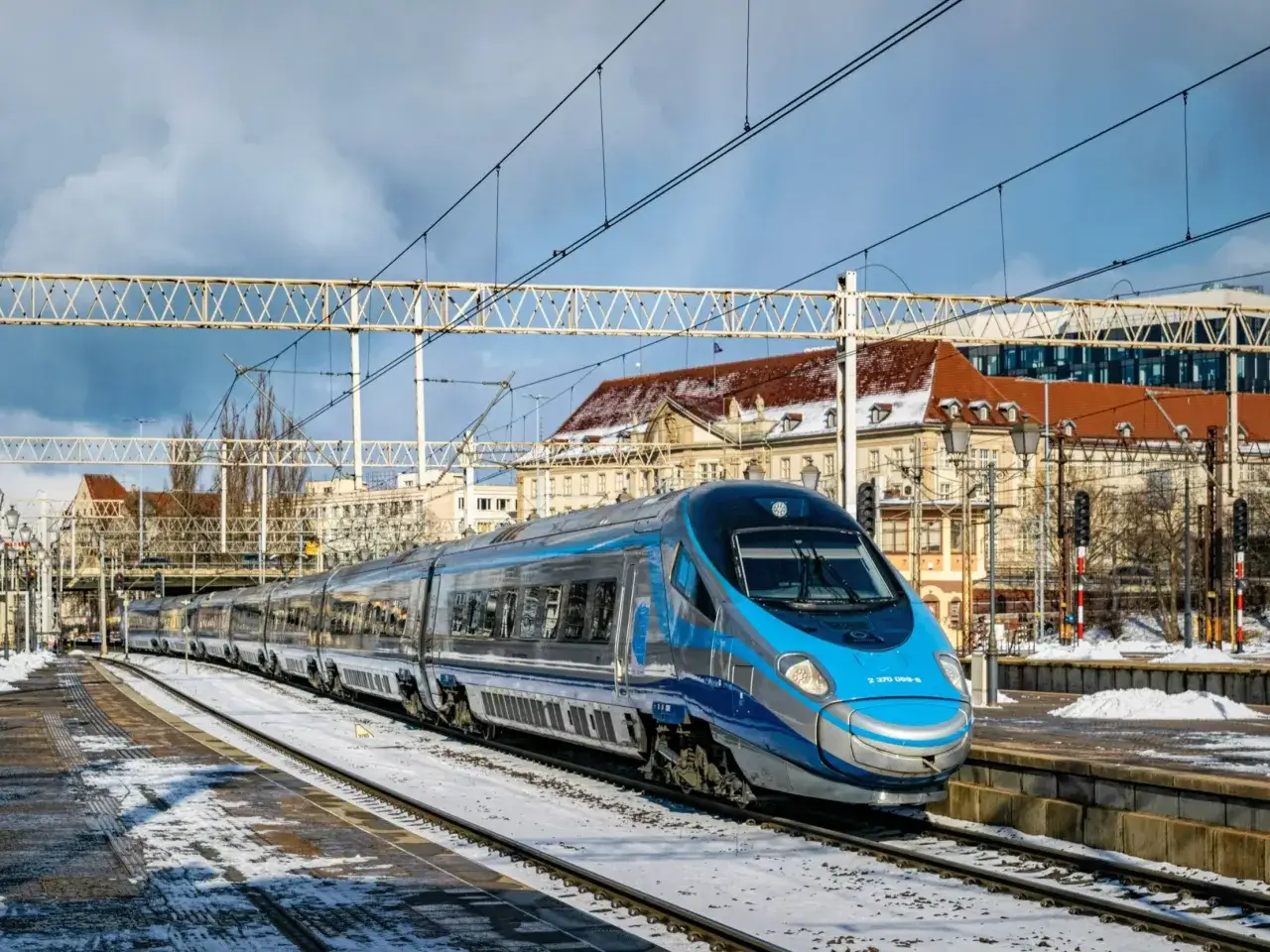 Nowoczesny pociąg Pendolino naśnieżonym torze, gotowy do podróży z Katowic do Warszawy.