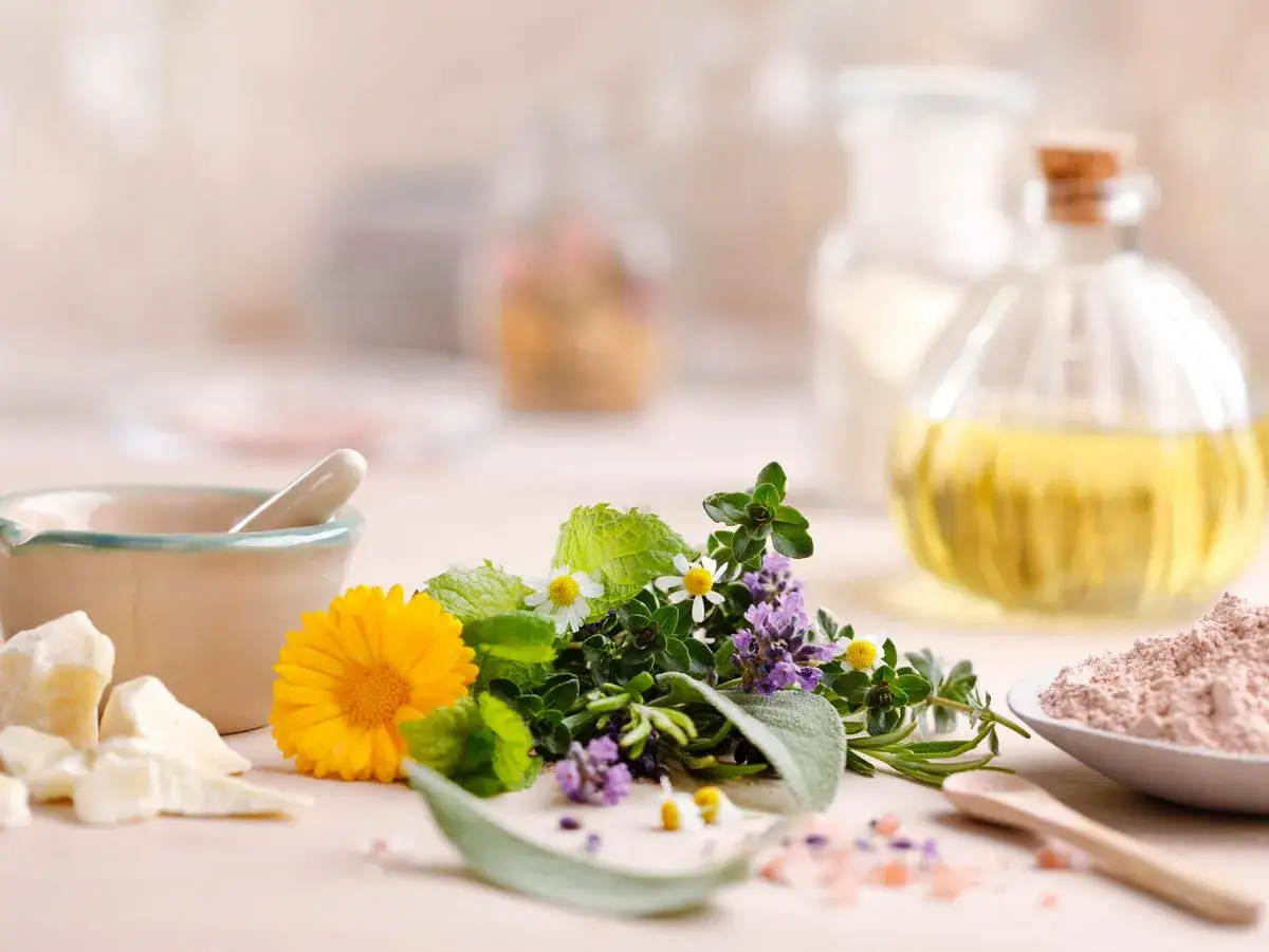 Zioła na uspokojenie: nagietek, lawenda, mięta, szałwia. Obok moździerz, olej i glinka.