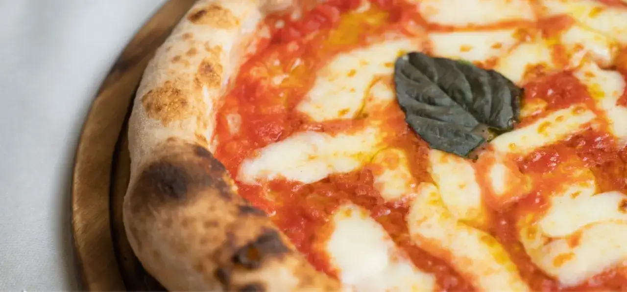 Idealna pizza margherita, gdy jest dzień pizzy. Puszyste ciasto, sos pomidorowy i ciągnący ser.