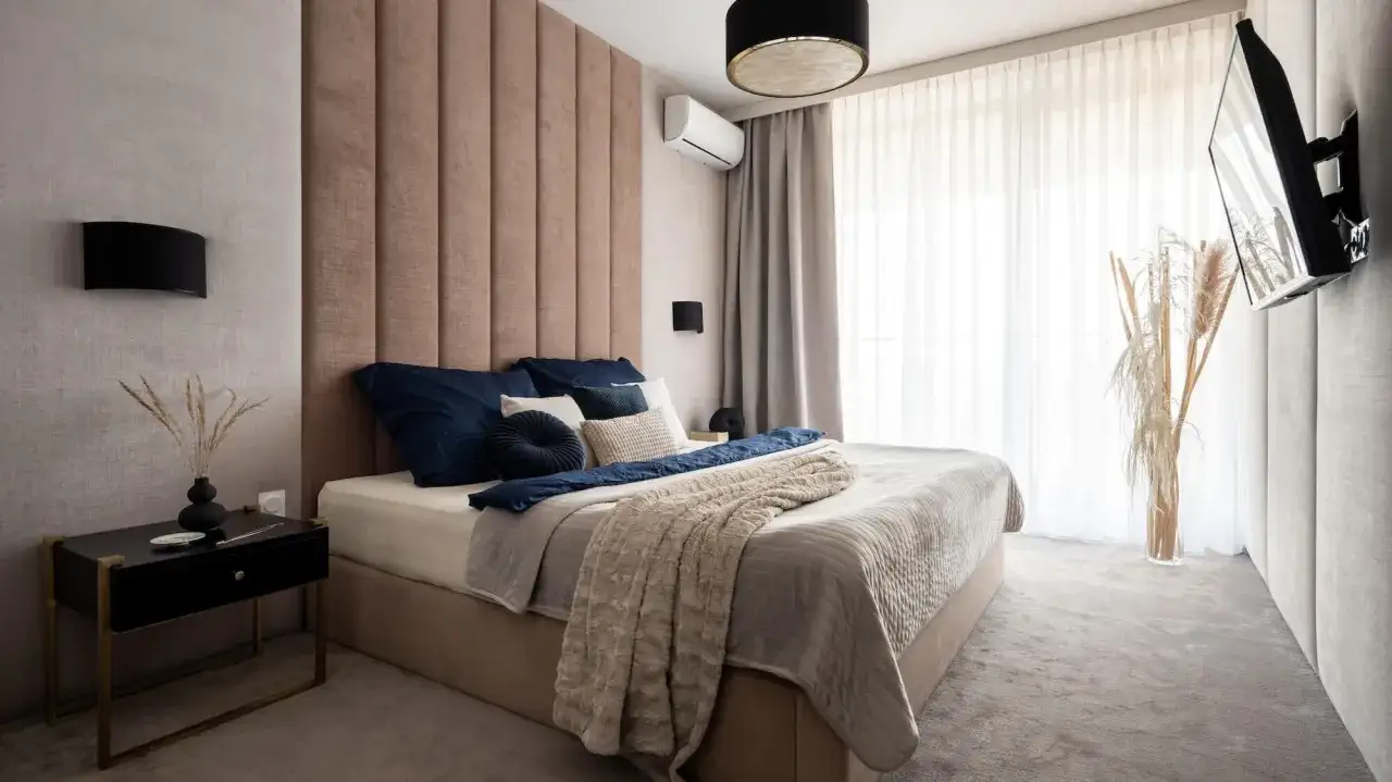 Elegancka sypialnia z telewizorem zamontowanym na ścianie. Idealna wysokość, by cieszyć się seansami.