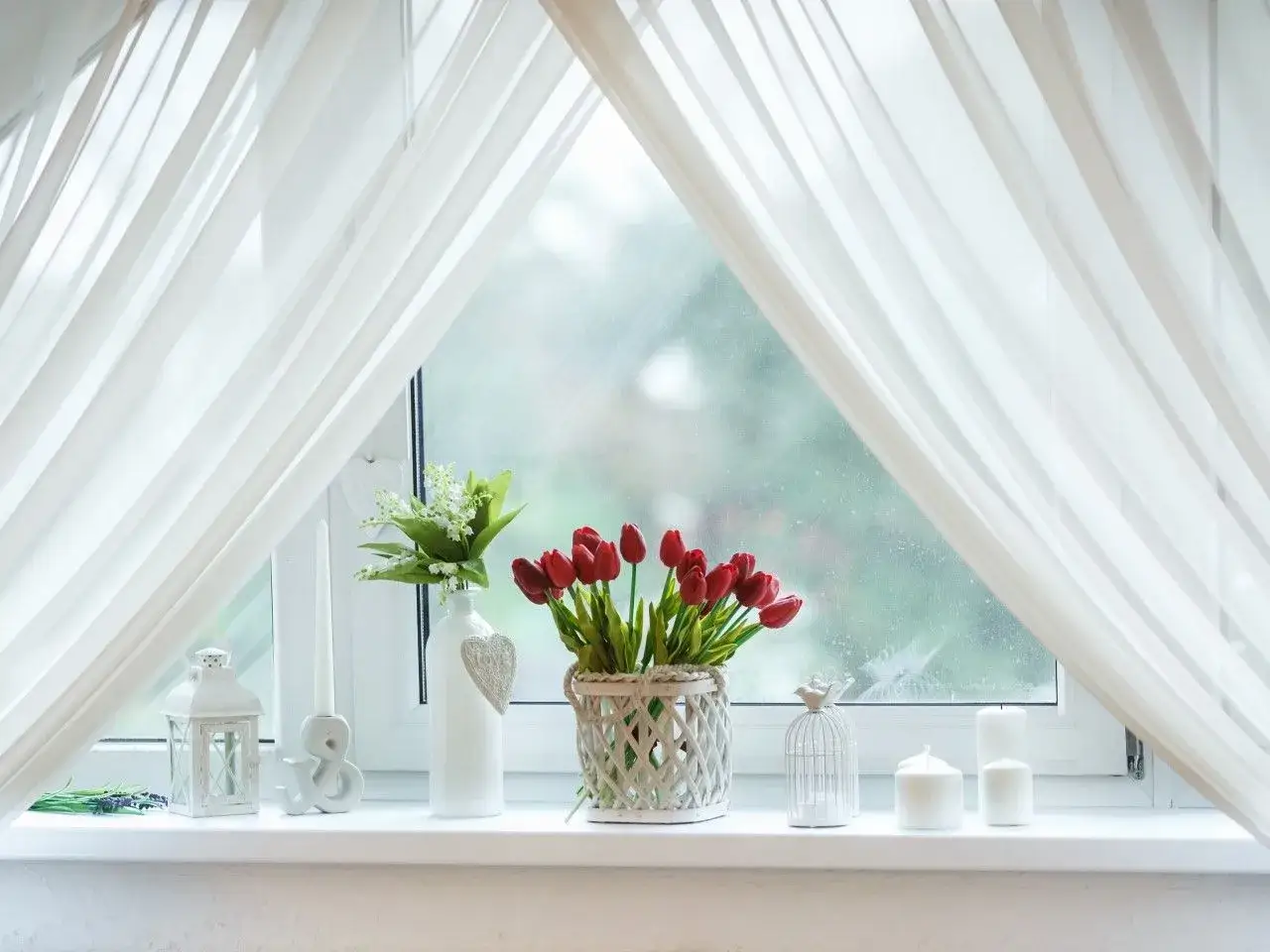 Urocze dekoracje okien: bukiet tulipan&oacute;w, konwalie, świece i lampion tworzą przytulne ozdoby na parapet.