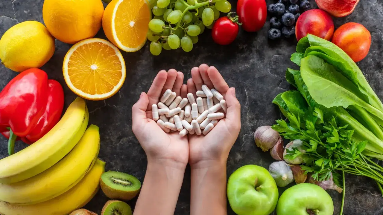 Dłonie trzymają kapsułki, obok świeże owoce i warzywa. Czy to suplementy z bioflawonoidami? Co to jest?