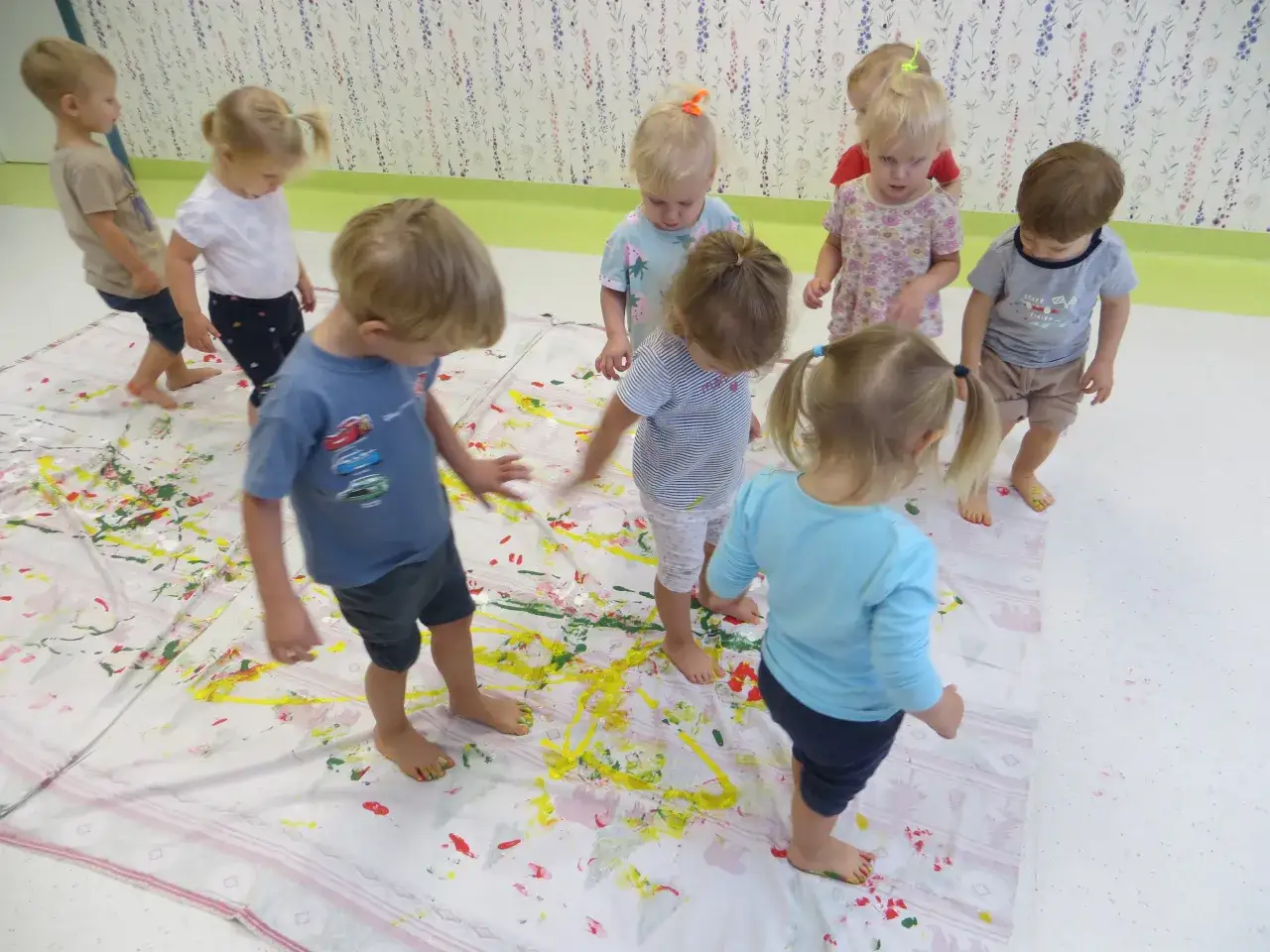 Dzieci malują stopami na wielkim płótnie. Tak wygląda radosny żłobek pełen kreatywności i kolorów.