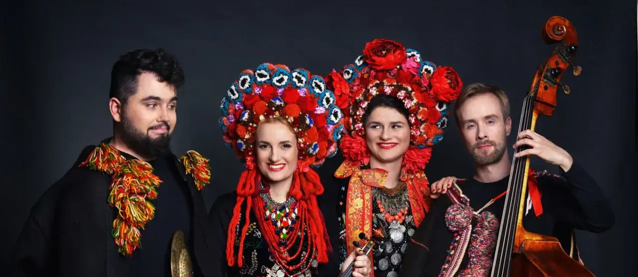 Zesp&oacute;ł w strojach ludowych, grający polski folk rock. Kobiety w barwnych czepcach, mężczyźni w tradycyjnych kamizelkach.