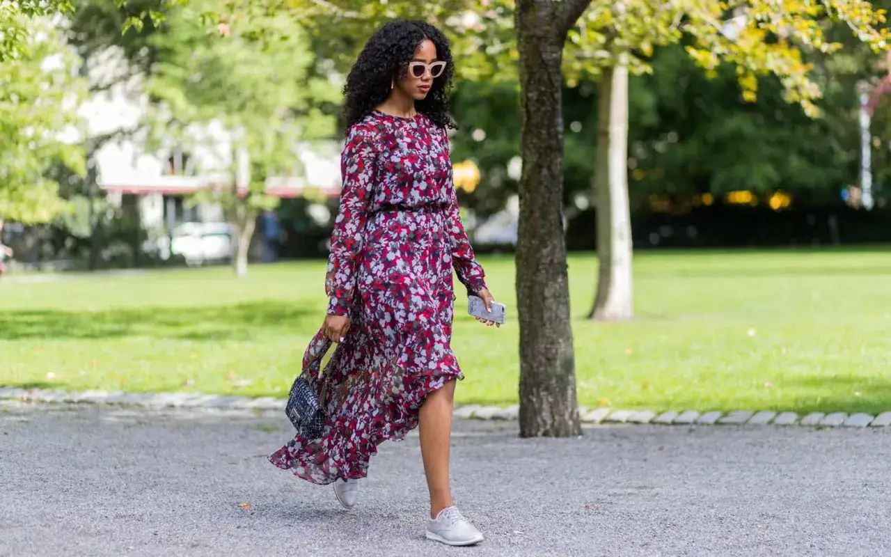 Kobieta w kwiecistej sukience i sneakersach. Idealne buty do zwiewnej sukienki na co dzień.
