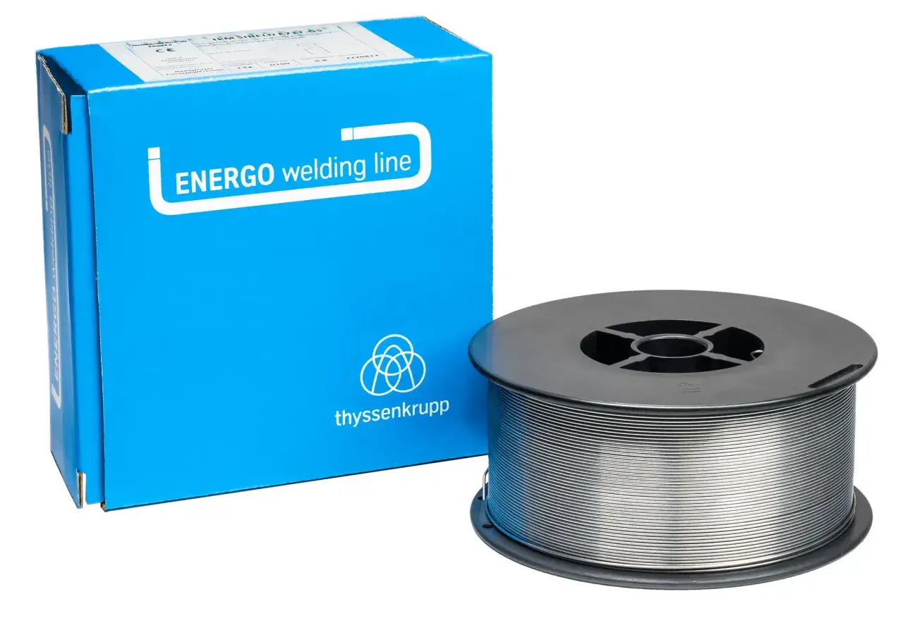 Drut do spawania bez gazu Energo welding line na szpulce, obok niebieskiego kartonu z logo thyssenkrupp.