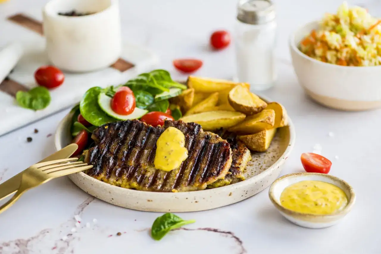 Grillowany stek z frytkami, sałatką i pysznym, żółtym sosem do grilla.
