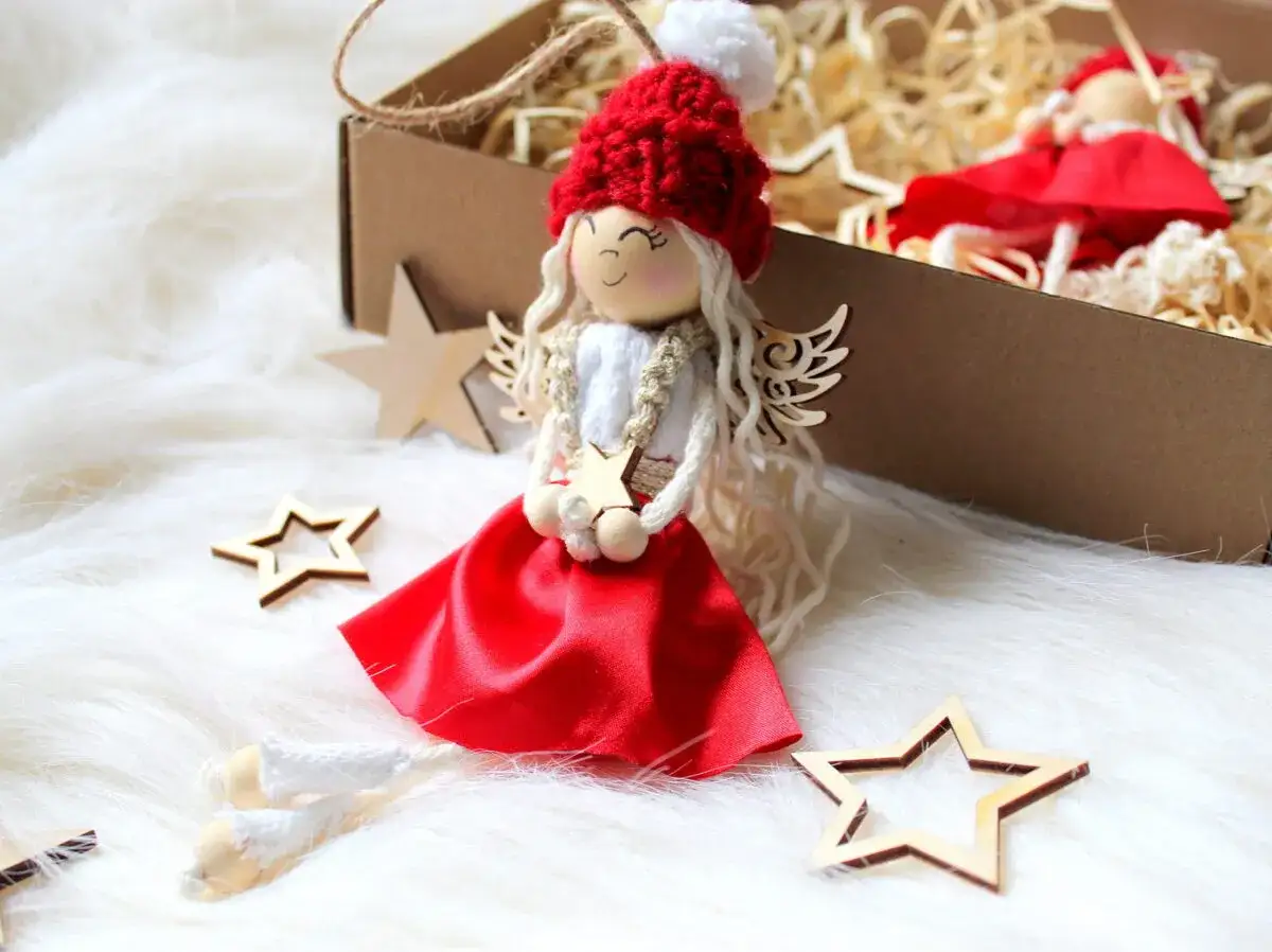 Uroczy aniołek z włóczki i materiału, z drewnianymi gwiazdkami, idealny przykład jak zrobić aniołka z różnych materiałów.