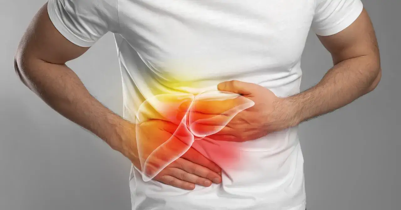 Mężczyzna trzyma się za brzuch, gdzie widoczna jest podświetlona wątroba. Może to symbolizować marskość wątroby objawy.