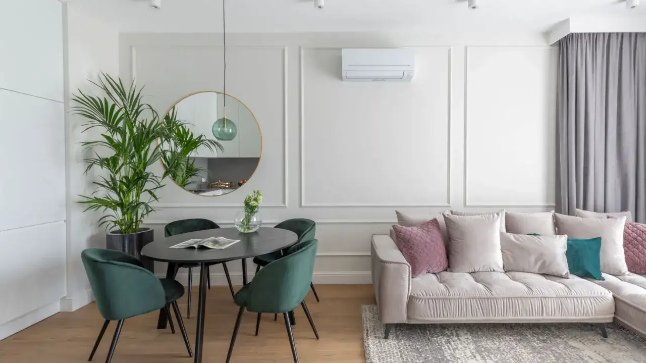 Elegancka jadalnia z zielonymi krzesłami i okrągłym lustrem. Sztukateria jak rozplanować? Delikatne zdobienia ścian dodają klasy.