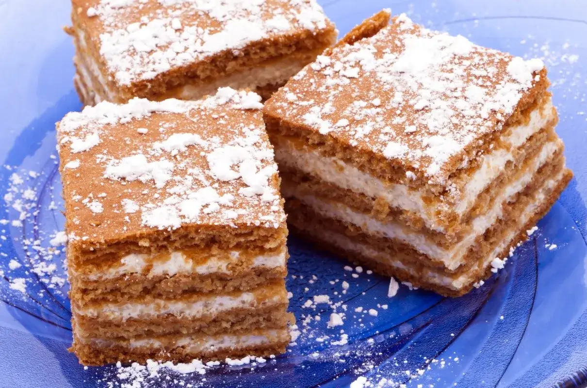 Miodownik Ani gotuje się w kuchni, a te pyszne kawałki z kremem i cukrem pudrem wyglądają apetycznie.