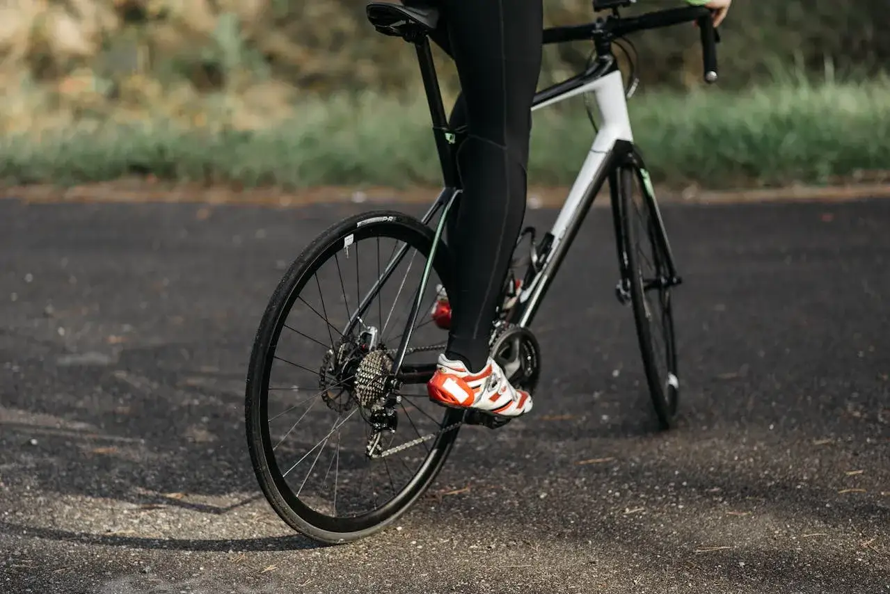 Rowerzysta w czerwono-białych butach pedałuje, dbając o odpowiednią **jaką kadencję na rowerze**.