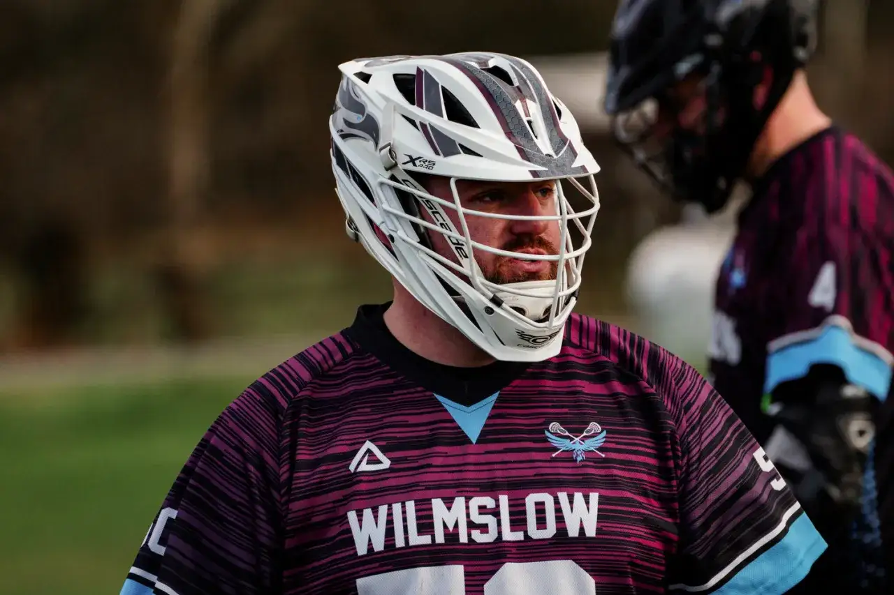 Gracz lacrosse w białym kasku i koszulce z napisem 
