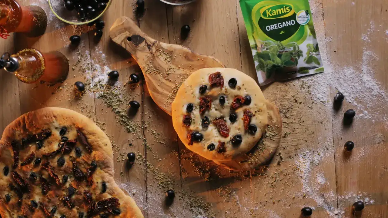 Pyszna focaccia z oliwkami i suszonymi pomidorami, idealna do podania z oliwą i ziołami.