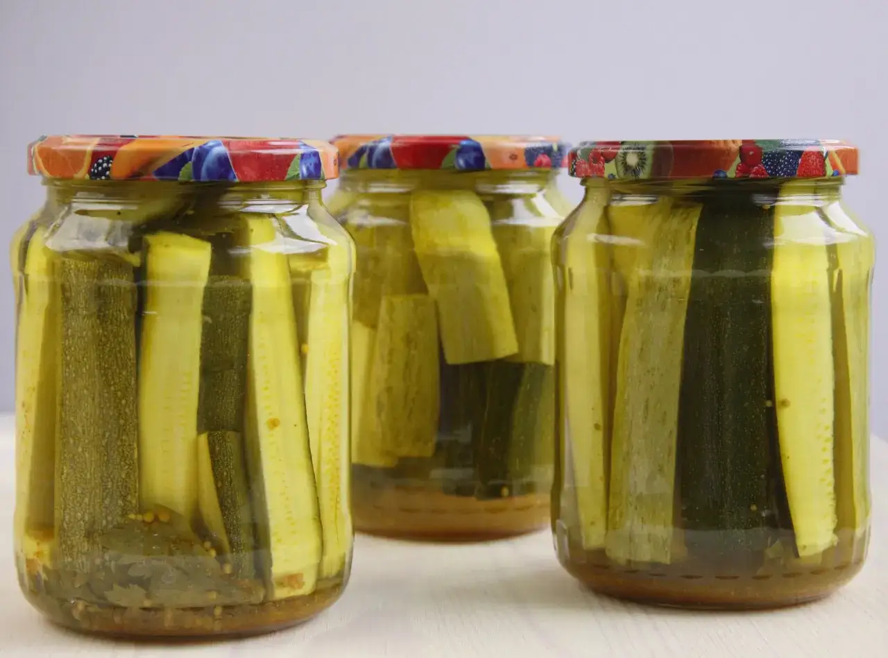 Słoiki z cukinią w zalewie słodko-kwaśnej z curry. Aromatyczne paski cukinii w zalewie z przyprawami, gotowe do spożycia.