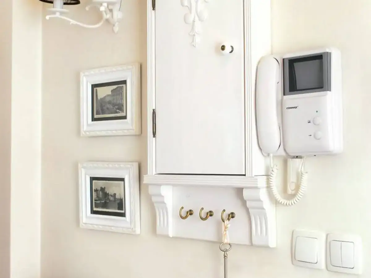 Elegancka zabudowa skrzynki elektrycznej w przedpokoju, z wieszakami na klucze i domofonem.