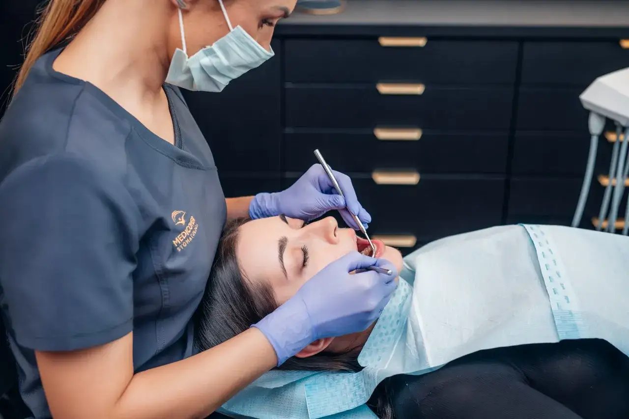 Dentysta w rękawiczkach bada zęby pacjentki. To, co widzi dentysta, to szczegółowy obraz jamy ustnej, gotowy do oceny stanu zdrowia.