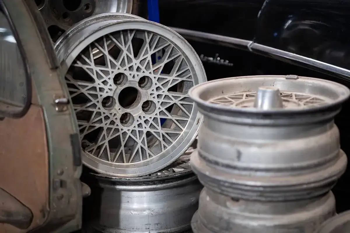 Stare felgi samochodowe, jedna z ażurowym wzorem, druga z centralnym elementem. Pomocne przy rozważaniach, jak dobrać wentyl do felgi.