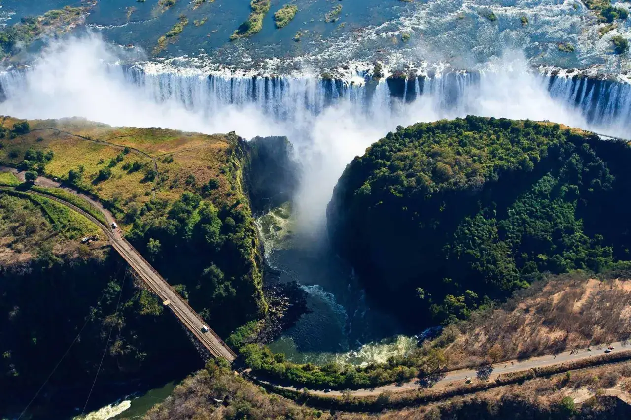 Wodospad Wiktorii, jedna z największych atrakcji turystycznych w Afryce, z mostem i drogą w oddali.