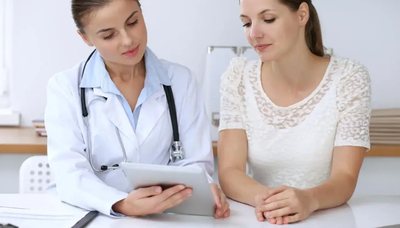 Lekarka wyjaśnia pacjentce, jakich leków nie można brać przed gastroskopią, pokazując informacje na tablecie.