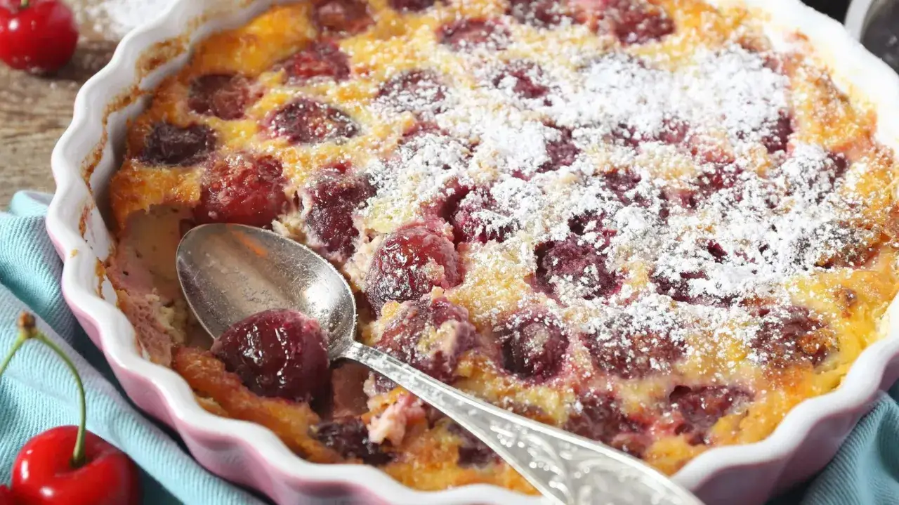 Pyszne clafoutis z wiśniami, posypane cukrem pudrem, czeka na łyżkę. Idealny deser na letnie popołudnie.