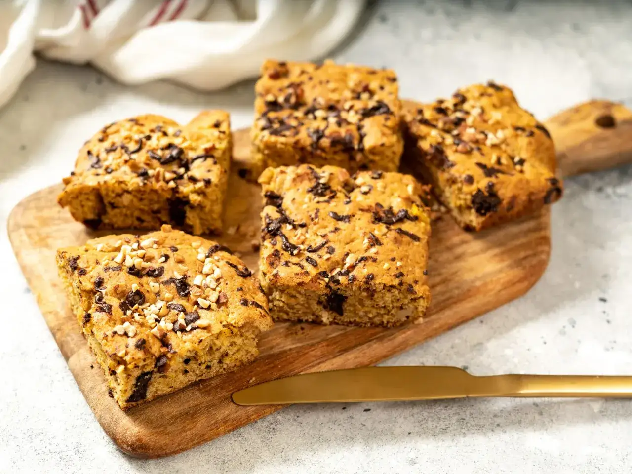 Sześć kawałków brownie i blondie, posypanych orzechami i czekoladą, leży na drewnianej desce.