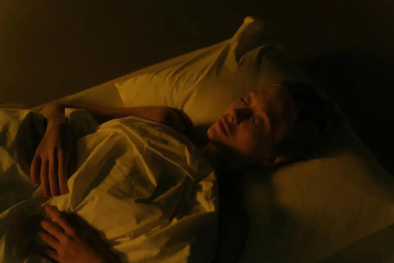 Kobieta śpi spokojnie, otulona kołdrą. Jej twarz wyraża błogi spokój, idealny do medytacji do snu.