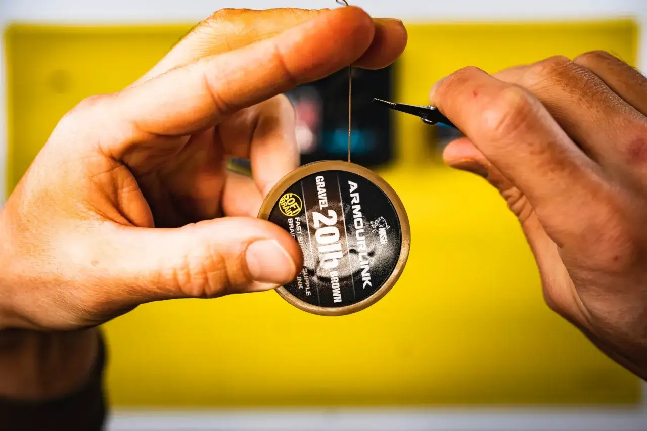 Ręce przygotowują przypon. Zobacz, jak zawiązać haczyk z włosem, by łowić skuteczniej.