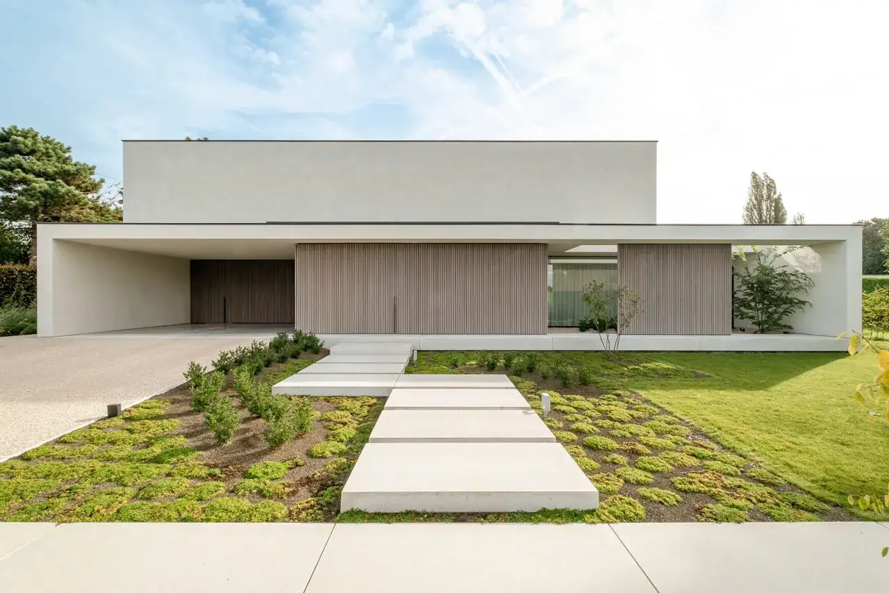 Nowoczesny dom z betonowym podjazdem i ścieżką z płyt. Świetny pomysł na wjazd do posesji z minimalistycznym ogrodem.
