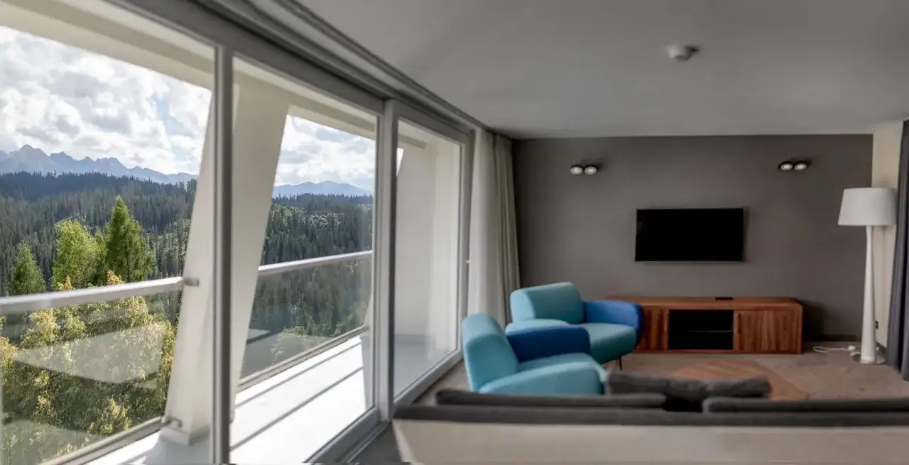 Widok z hotelu Harnaś Wierch Buńdowy w Bukowinie Tatrzańskiej na g&oacute;ry i las. Wnętrze z niebieskimi fotelami.