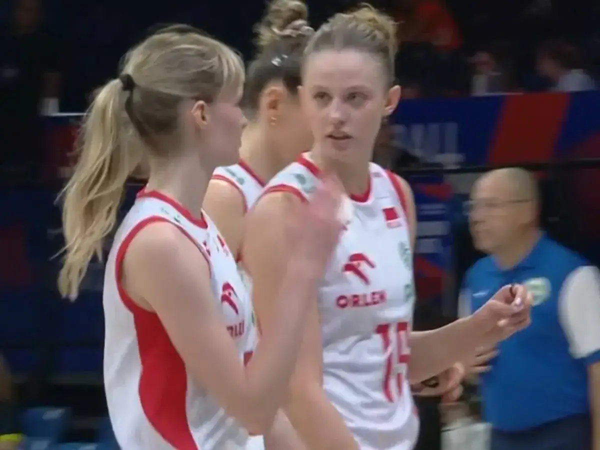 Siatkarki w biało-czerwonych strojach, dyskutujące na boisku. Ich forma może wpłynąć na ligę narodów siatkarek tabelę.