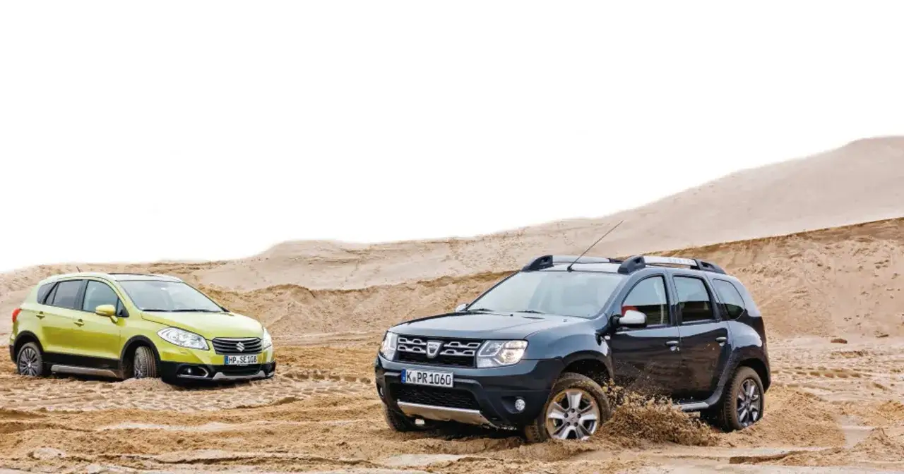 Dwa SUV-y, żółte Suzuki SX4 i ciemny Dacia Duster, grzęzną w piasku. Pojemność baku Suzuki SX4 jest kluczowa podczas takich wypraw.