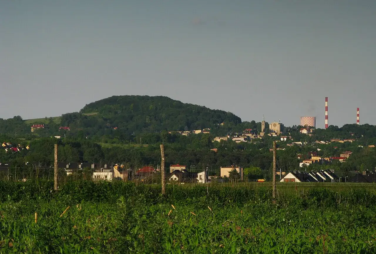 Zielone wzgórze Góra Dorotka góruje nad miasteczkiem z kościołem i kominami.