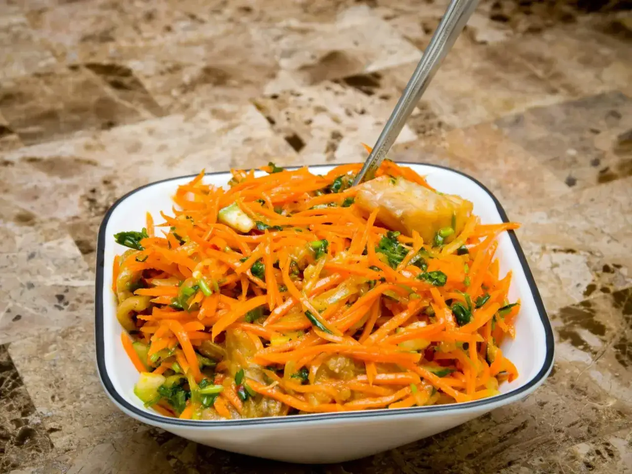 Pyszna sur&oacute;wka z marchewki, z dodatkiem zieleniny i kawałk&oacute;w warzyw, podana w białej miseczce. Idealna na lekki posiłek.