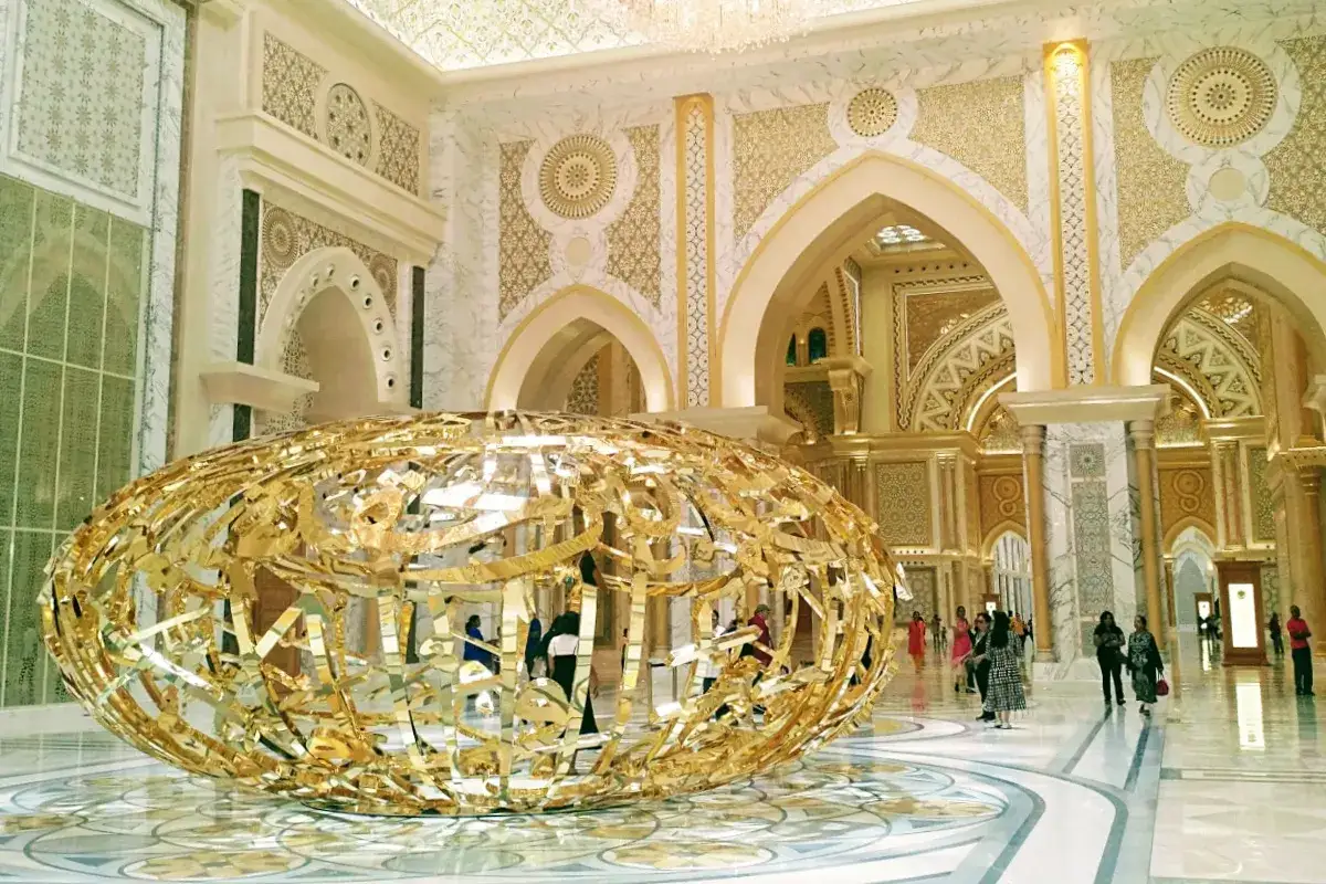 Złota, ażurowa rzeźba w holu Qasr al Watan, odbijająca bogato zdobione wnętrze pałacu.