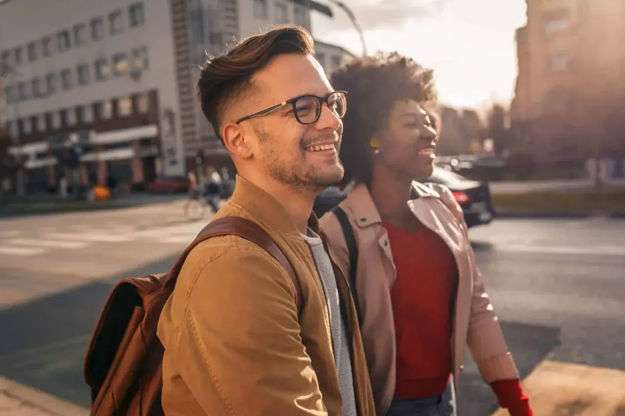 ENTP i INFJ w drodze na spotkanie, śmieją się, ciesząc się słońcem i miejskim krajobrazem.