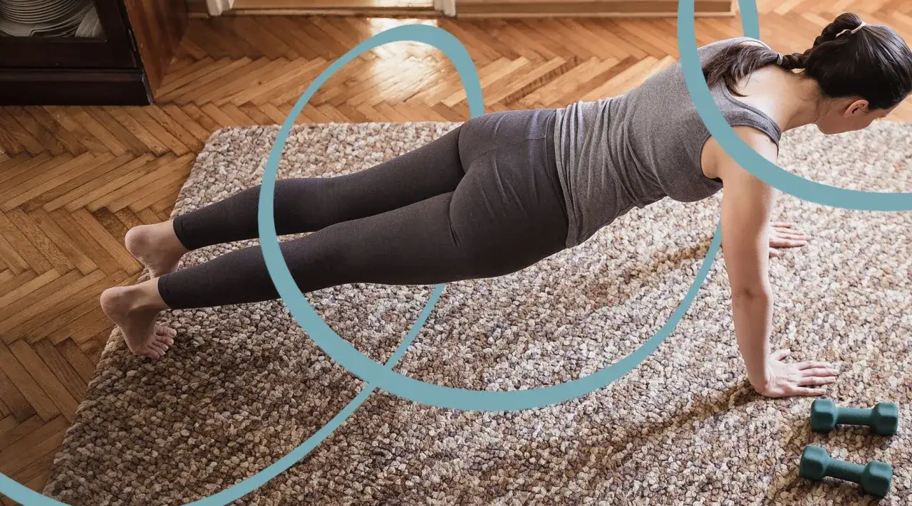 Kobieta w pozycji deski na dywanie. Pilates wzmacnia ciało i poprawia postawę. Dwa małe hantle leżą obok.