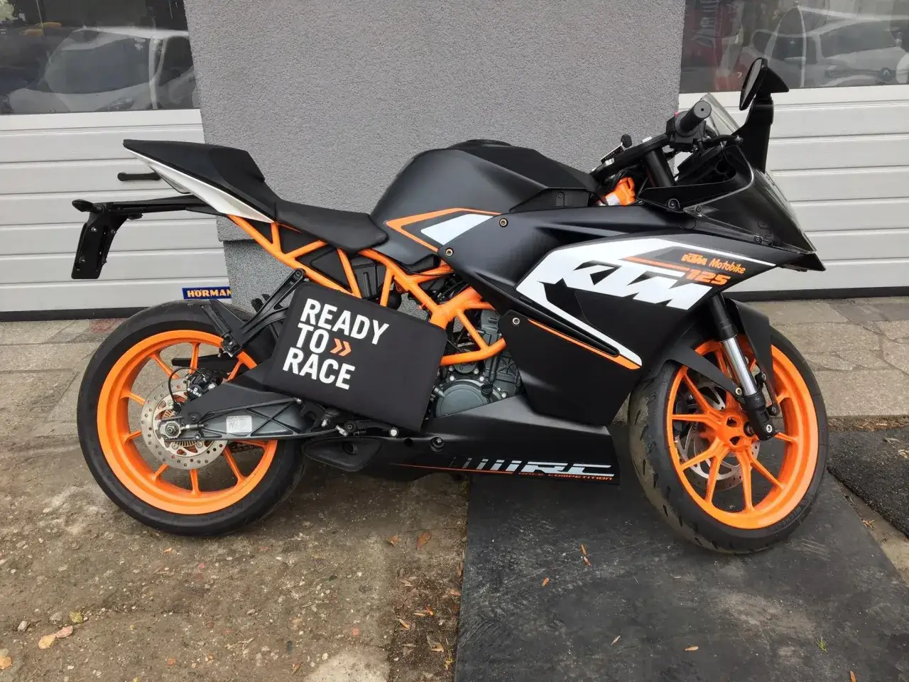Czarny KTM 125 z pomarańczowymi felgami, idealny jako pierwszy motor na kat B. Napis 